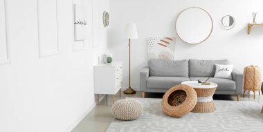 Stylish interior of living room with sofa, chest of drawers and mirrors 