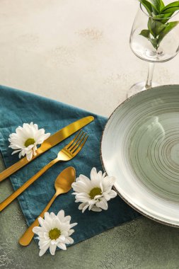 Table setting with chamomile flowers on white and green background