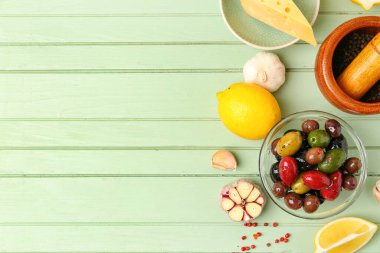 Composition with bowl of delicious olives and different products on color wooden background