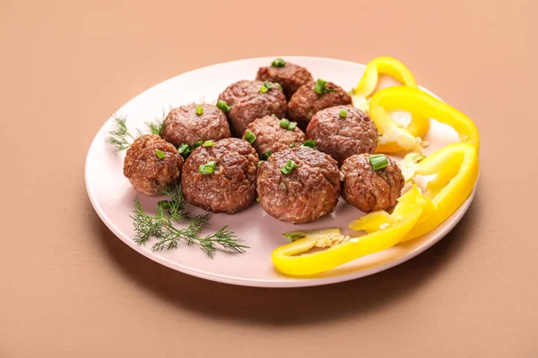 Plate with tasty meat balls, cut green onion, dill and bell pepper on brown background