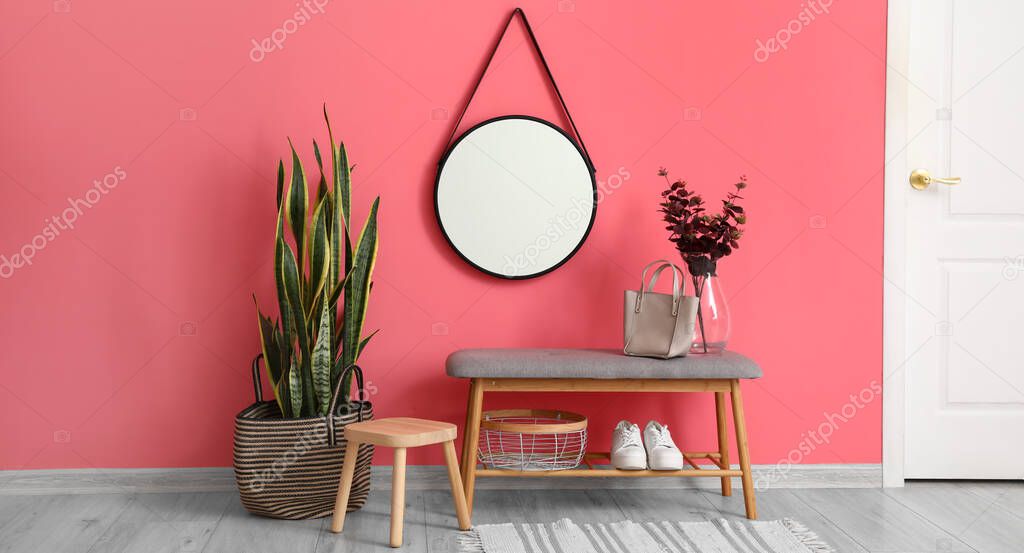 Interior of stylish hall with soft bench, stool, houseplant and mirror
