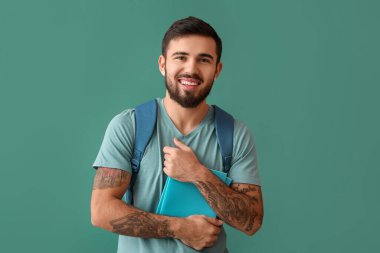 Handsome tattooed student on green background