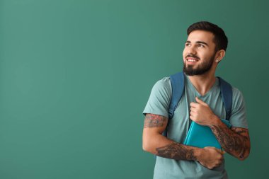 Handsome tattooed student on green background