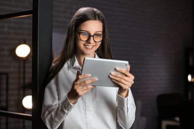 Smiling businesswoman working with tablet computer in office at night
