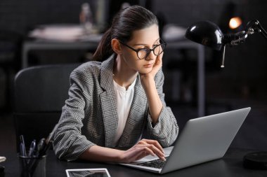 Beautiful businesswoman working with laptop in office at night