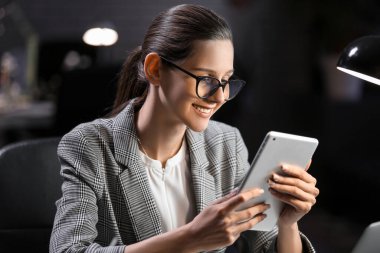 Beautiful businesswoman working with tablet computer in office at night