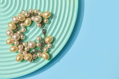 Showcase pedestal with pearl bracelet on blue background