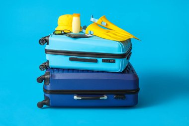 Suitcases with beach accessories, passports and tickets on color background