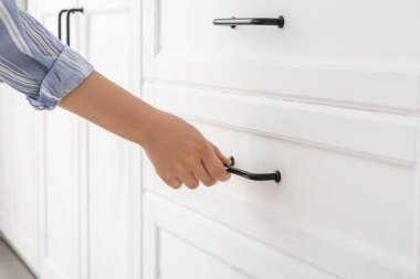 Woman opening drawer in light kitchen, closeup