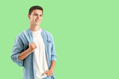 Teenage boy with backpack on green background