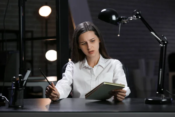 Upset businesswoman working with notebook in office at night