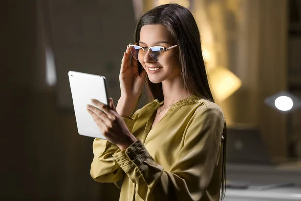 Smiling businesswoman with tablet computer working in office at night