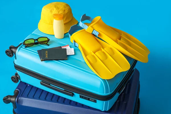 Suitcases with beach accessories, passports and tickets on color background, closeup