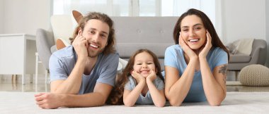 Happy family lying on soft carpet in living room