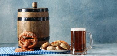Mug of fresh beer, snacks and wooden barrel on table