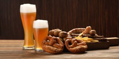 Glasses of cold beer and snacks on table
