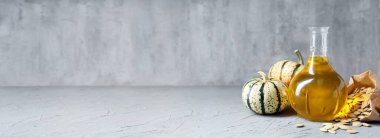 Jug of pumpkin seed oil on grey background. Banner for design
