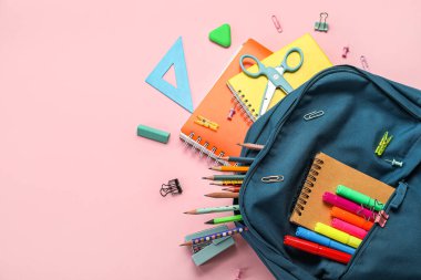 School backpack with stationery supplies on pink background