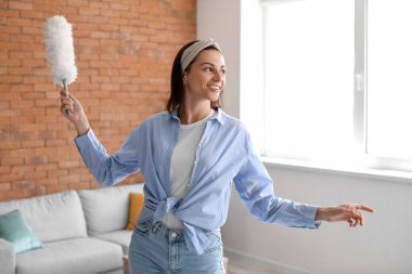 Young housewife with duster at home