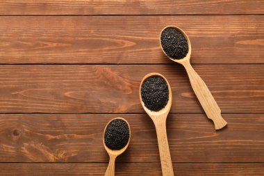 Spoons with sesame seeds on wooden background