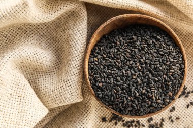 Wooden bowl of black sesame seeds on table, closeup