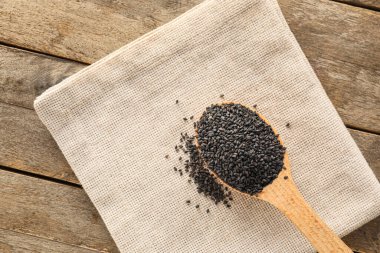 Spoon with black sesame seeds on wooden table