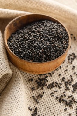 Wooden bowl of black sesame seeds on table, closeup