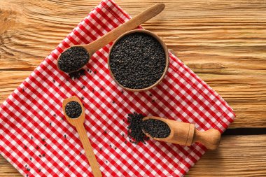 Bowl, spoons and scoop with black sesame seeds on wooden table