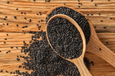 Spoons with black sesame seeds on wooden background, closeup
