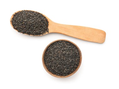Wooden bowl and spoon of black sesame seeds on white background