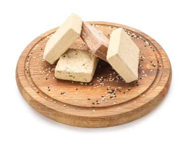 Wooden board with sweet sesame halva on white background