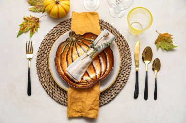 Stylish table setting with autumn decor and pumpkin shaped plate on light background