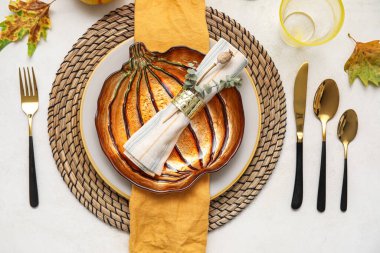 Stylish table setting with autumn decor and pumpkin shaped plate on light background