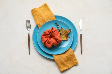 Table setting with autumn decor and pumpkin made of napkin on light background