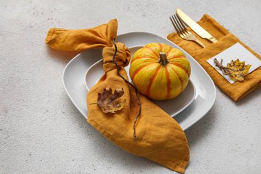Simple table setting with beautiful autumn decor and pumpkin on light background, closeup