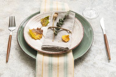 Dinnerware with autumn leaves and eucalyptus branch on grunge table
