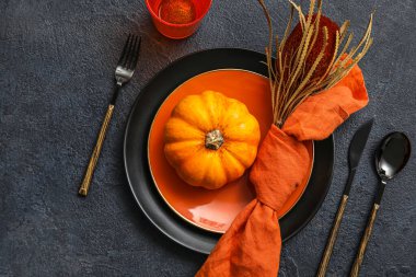 Stylish table setting with pumpkin and autumn decor on dark background