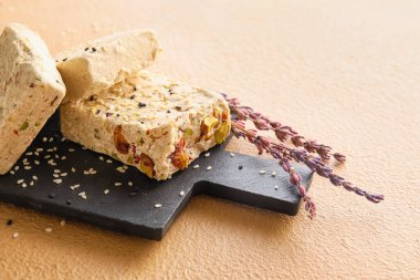 Board with tasty sesame halva on color background, closeup