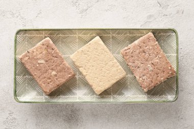 Plate with pieces of tasty sesame halva on light background