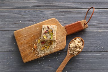 Board of tasty sesame halva with pistachios on dark wooden background