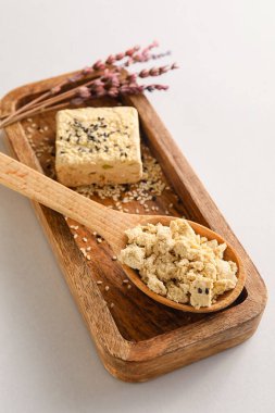 Wooden board with sweet sesame halva on white background