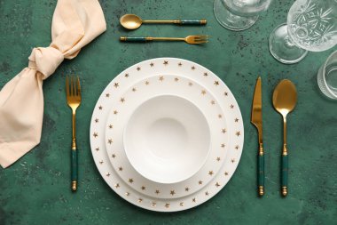 Elegant table setting with plates, cutlery and glasses on green background