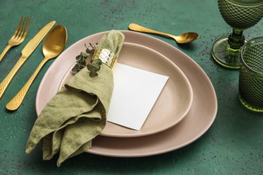 Dinnerware with blank card and eucalyptus branch on green table