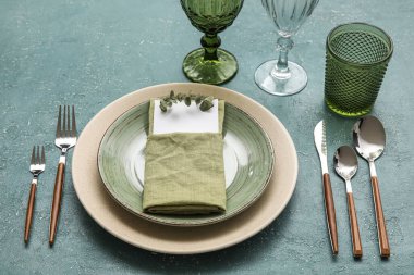 Elegant dinnerware with eucalyptus branch and blank card on color table