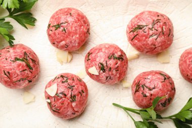 Raw meat balls with herbs and garlic on white plate, closeup