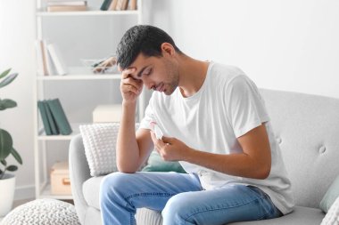 Upset young man holding tissue with nasal blood at home