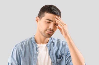 Young man with nosebleed on light background, closeup
