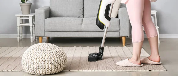 Woman vacuuming carpet in living room