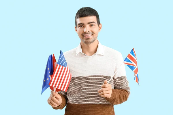 Young man with different flags on blue background