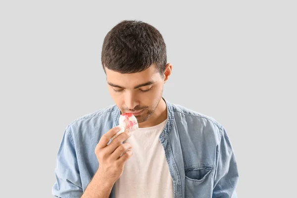 Young Man Wiping Nosebleed Tissue Light Background Closeup — Stockfoto